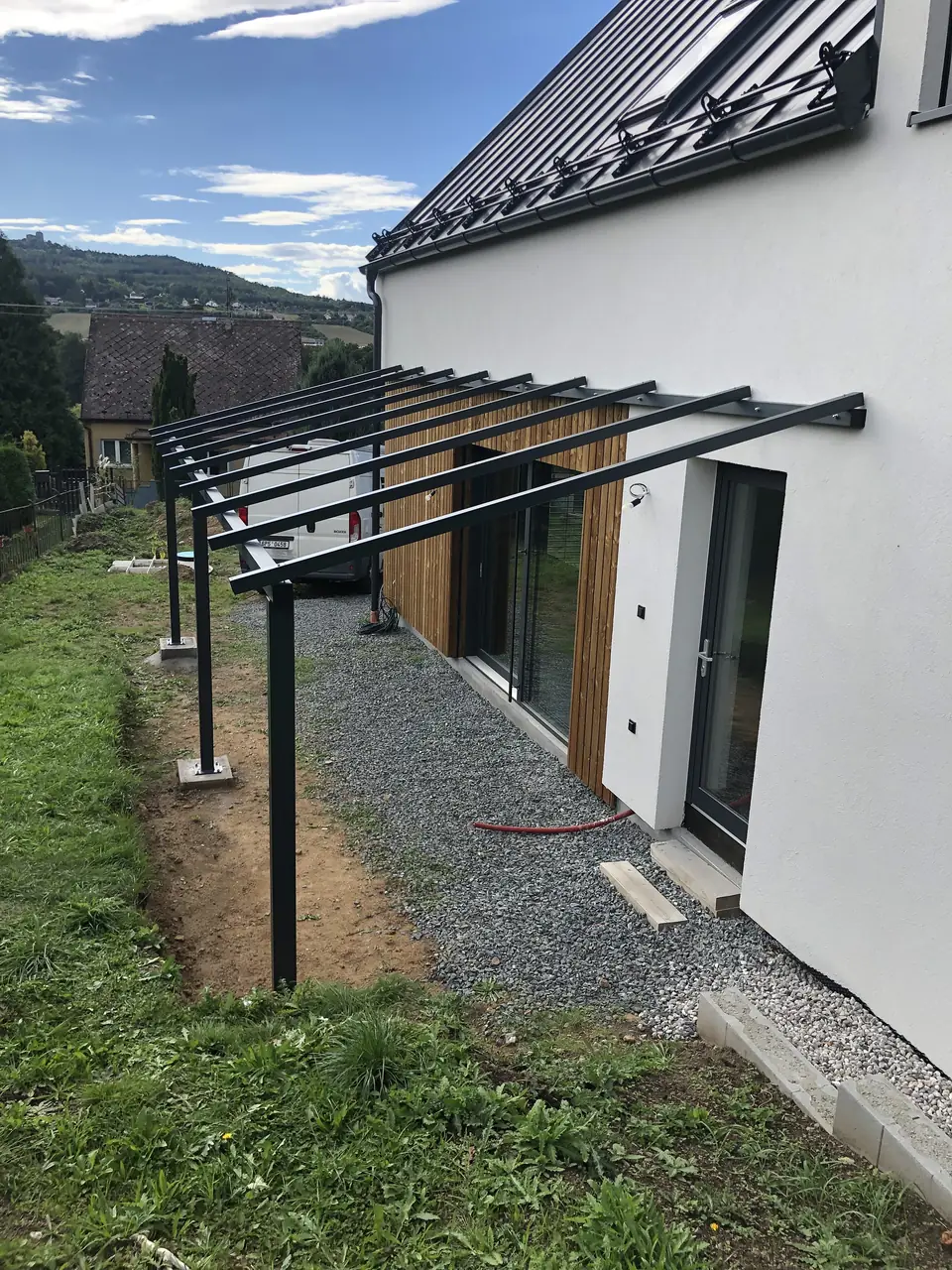 Ocelová pergola podél fasády rodinného domu