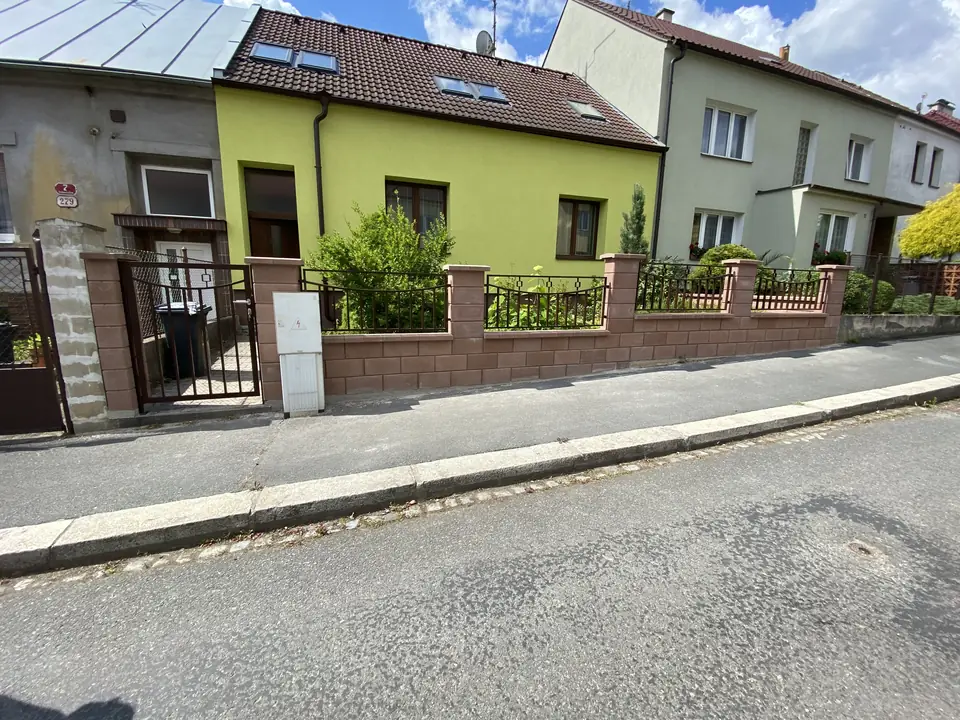 Hnědý plot a branky podél řadové zástavby